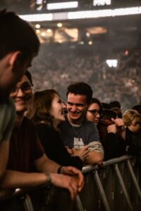 A lively crowd at a concert enjoying the performance with smiles and laughter.