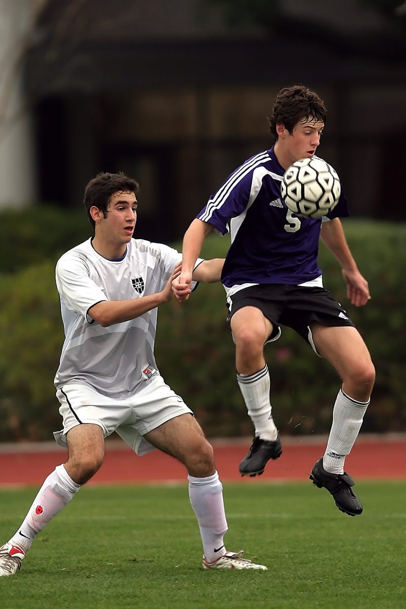 Two teens engaged in an intense outdoor soccer game, focusing on skill and strategy.